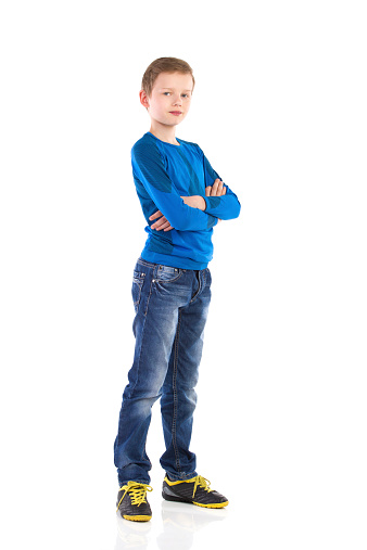 Boy posing with arms crossed. Full length studio shot isolated on white.