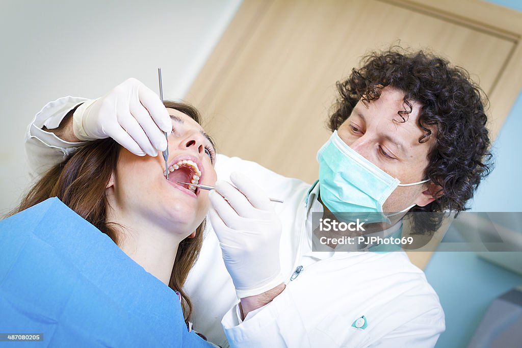 Dentist with dental tools Dentist using dental tools on young woman patient  - Tool for teeth cleaning  20-24 Years Stock Photo