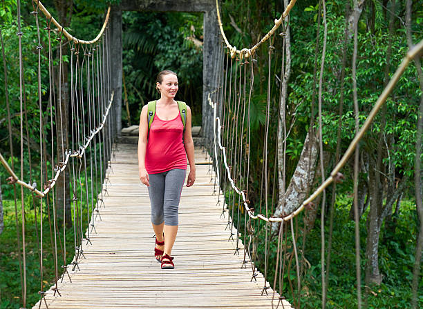 istock Smiling woman hiker crossing suspension bridge 487081170