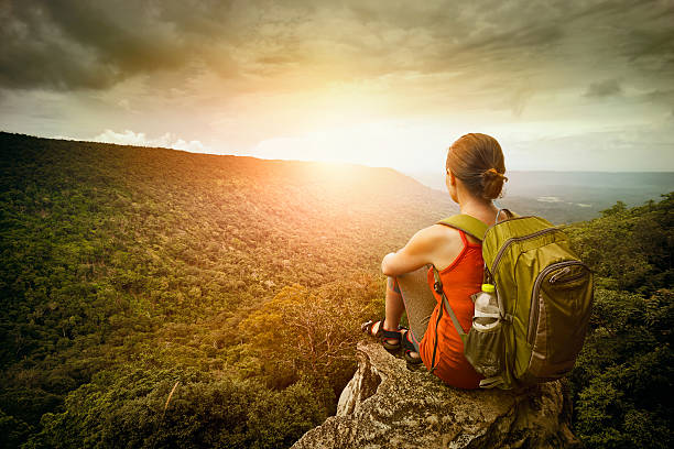 hiker sits on edge of the cliff and enjoying sunrise stock photo