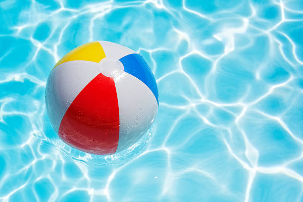 Beach ball in swimming pool Beach ball floating in swimming pool abstract concept for summer vacations, relaxation and fun in the sunshine beach ball stock pictures, royalty-free photos & images