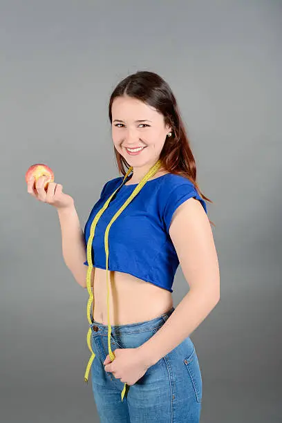 Photo of Happy young woman dieting, tape measure around neck