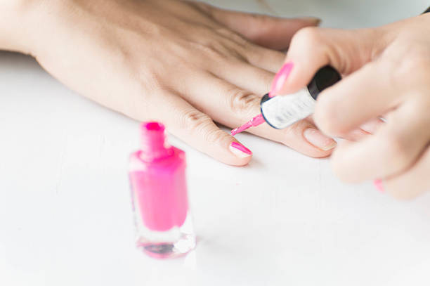 istock Woman applying pink nail polish on hand 487087100