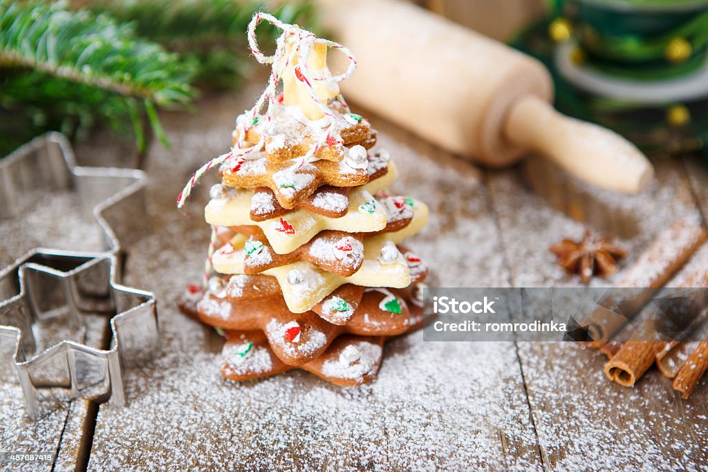 Homemade baked Christmas gingerbread tree on vintage wooden back Homemade baked Christmas gingerbread tree on vintage wooden background. Anise, cinnamon, baking roll, star forms and decoration utensils. With icing sugar als snow. Selfmade gift for xmas. 2015 Stock Photo
