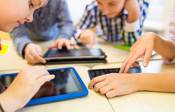 à proximité de l'école enfants jouant avec une tablette pc - using tablet photos et images de collection