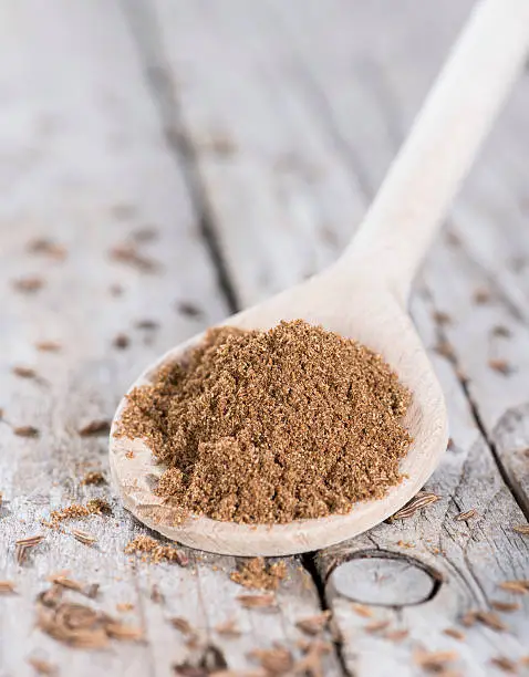 Caraway Powder on a wooden spoon (against vintage wooden background)