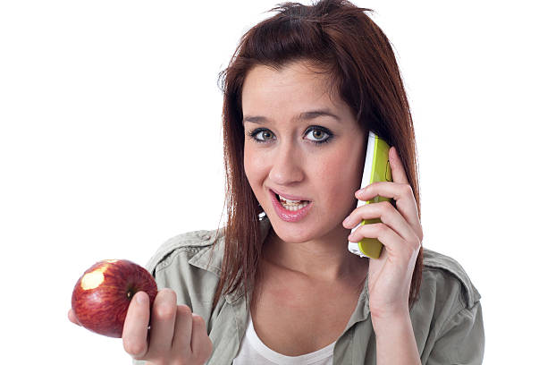 Worried girl speaking on the phone and eating an apple