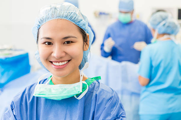 mujer asiática quirúrgica pasante en el hospital quirófano durante la cirugía - hair net nurse scrubs asian ethnicity fotografías e imágenes de stock
