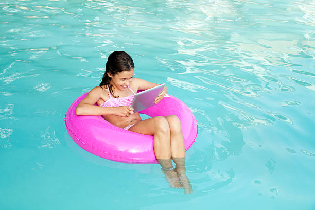 istock Eigth years old reading a book in a swimming pool 487113314
