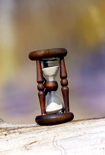 istock hourglass on wooden log surface 487113572