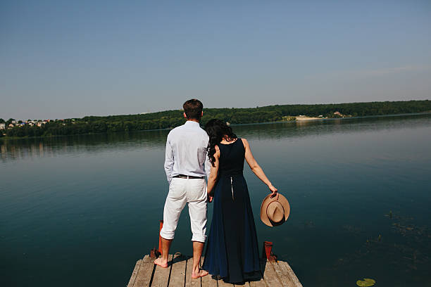 istock Young couple standing on a deck by the water 487120954