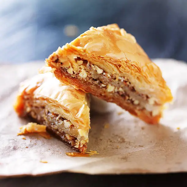 two baklava halves sitting on wax paper shot with selective focus stacked on top of each other