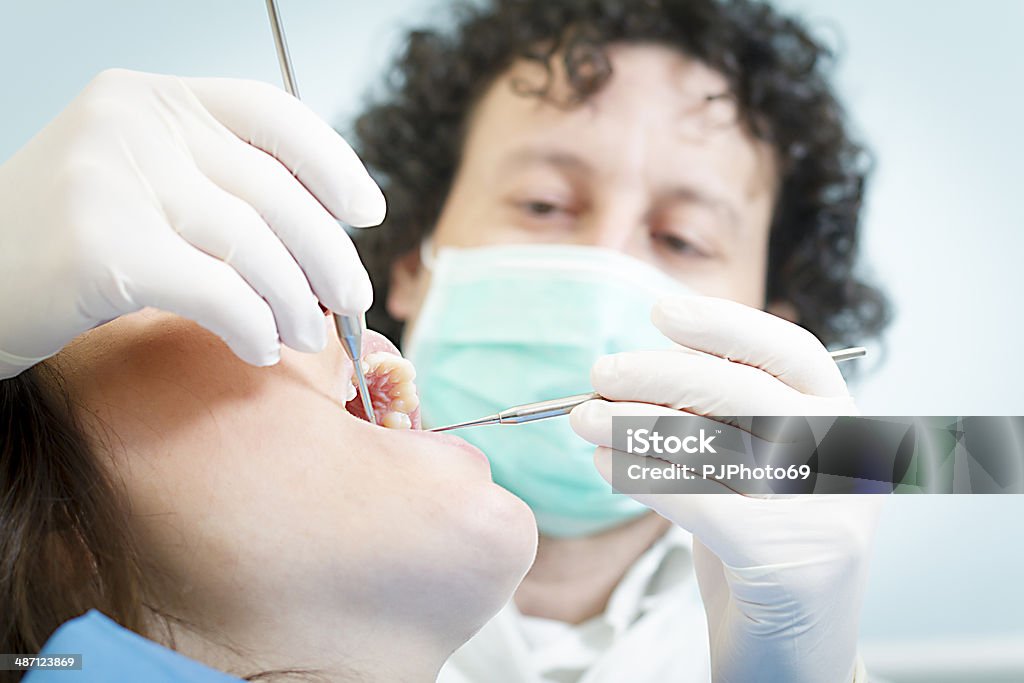 Dentist with dental tools Dentist using dental tools on young woman patient  - Tool for teeth cleaning  20-24 Years Stock Photo