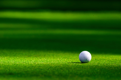 Selective focus on a golf ball on green. No people and room for copy space.