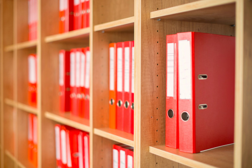 Red ring binders on shelf,  shallow depth-of-field.