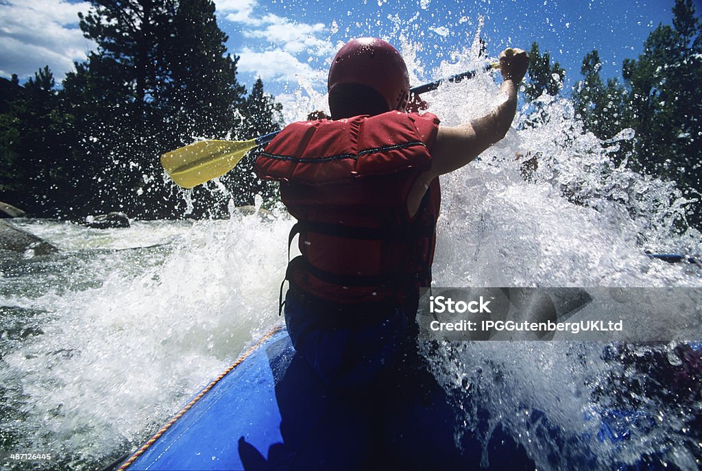 Kayaker Paddling Through Rapids Rear view of a male kayaker paddling through rapids Rapids - River Stock Photo