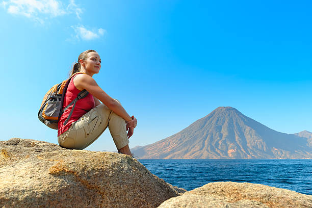 Hiker with backpack relaxing on a rock stock photo