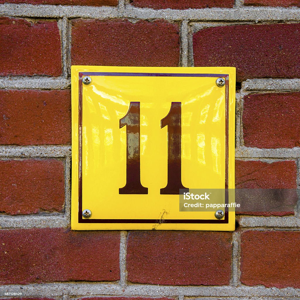 Number 11 Enameled house number eleven. Brown lettering on a yellow background. Alphabet Stock Photo