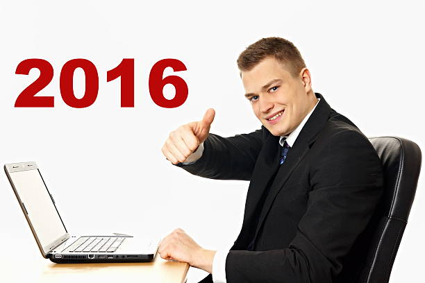 Happy new 2016 year. Handsome young businessman at the computer shows finger up for happy new year.