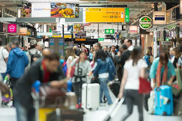 Color image of people walking in the terminal at Schiphol International Airport in the Netherlands. Selective focus on background with copy space.