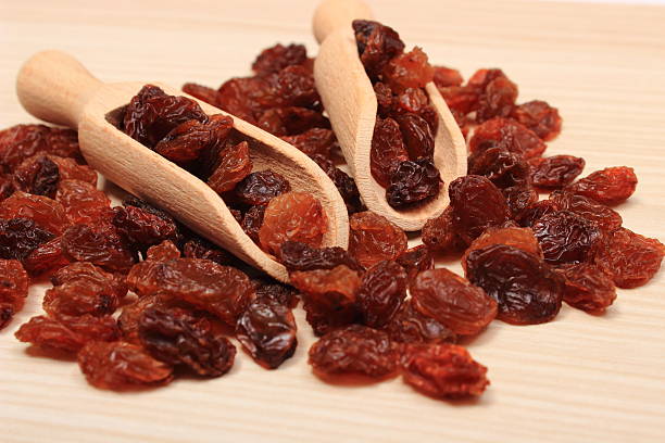 istock Brown raisins with spoon on wooden table, healthy eating 487136592