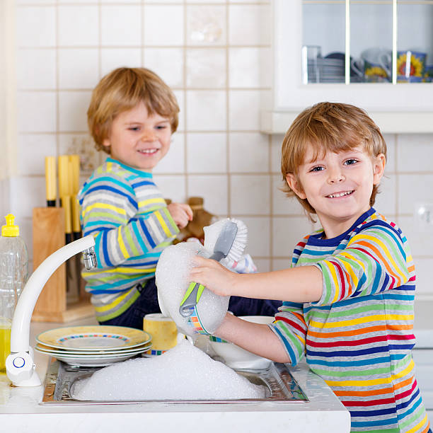 istock Funny twin boys helping in kitchen with washing dishes 487137184