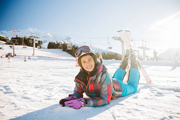 Teenage girl skiing in Italian Alps. Teenage girl skiing in Italian Alps, lying on snow and looking at camera. Winter, daytime. Sunny weather. 13 14 years child teenage girls lying down stock pictures, royalty-free photos & images