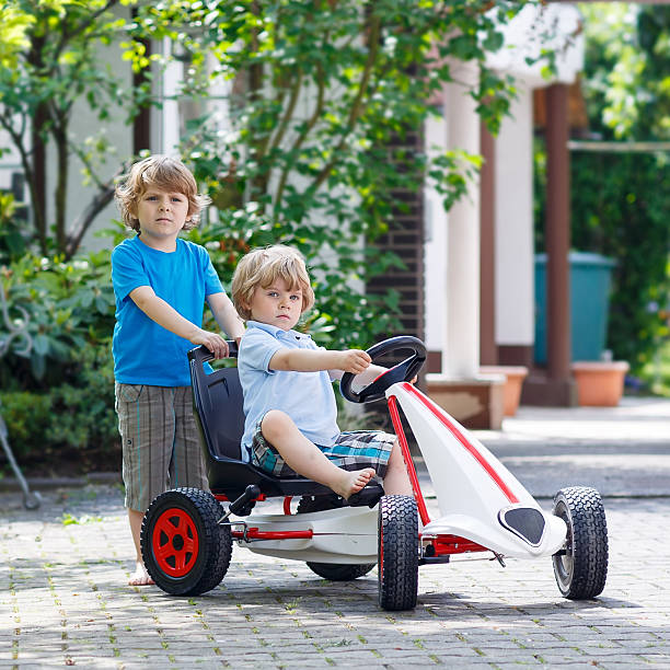 dos hermanos felices niños divirtiéndose con coche de juguete - car child teamwork sports race fotografías e imágenes de stock