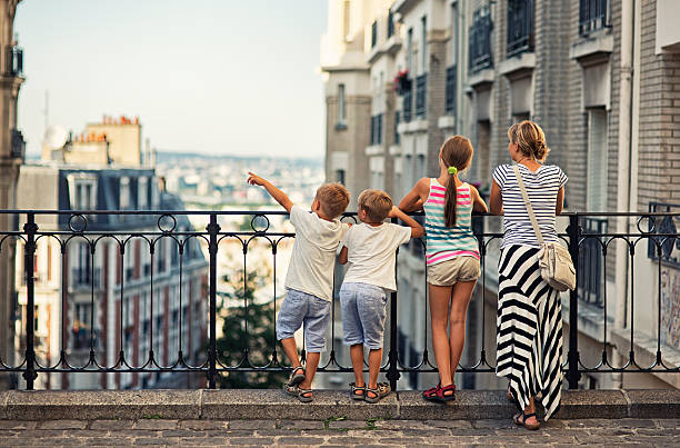 Family visiting Paris, Montmartre Mother and kids visiting Paris. They are watiching beautiful Paris view from the top of Montmartre. One of the boys is pointing at something. ile de france photos stock pictures, royalty-free photos & images