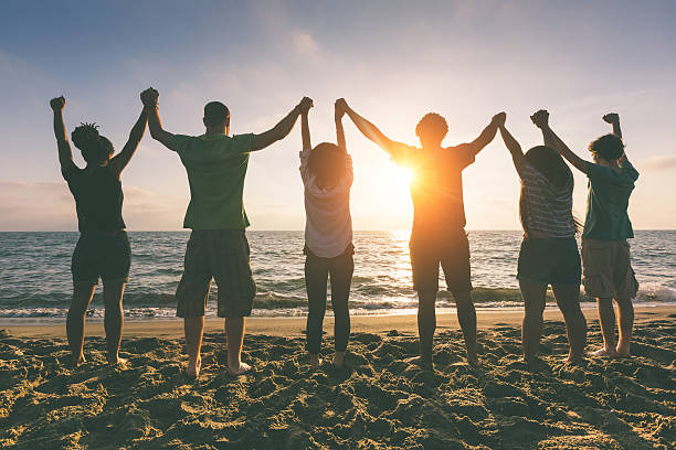 istock Multiracial Group of People with Raised Arms looking at Sunset 487153171