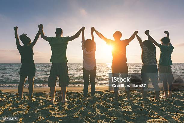 Multirracial Grupo De Pessoas Com Os Braços Levantados Na Procura De Pôr Do Sol - Fotografias de stock e mais imagens de De Mãos Dadas