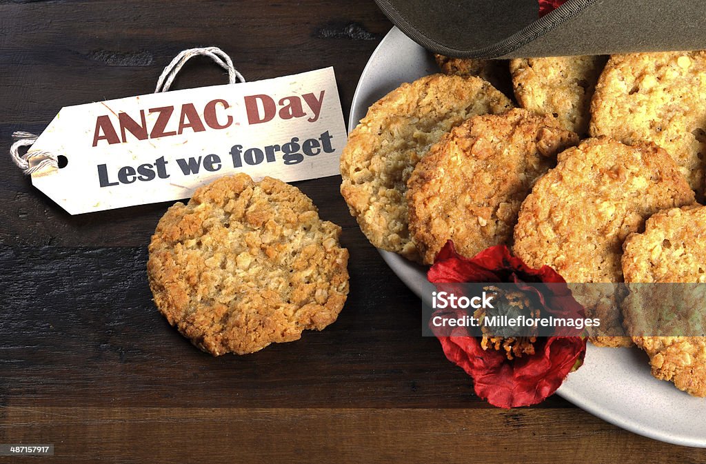 Australian army slouch hat and traditional Anzac biscuits Australian army slouch hat and traditional Anzac biscuits on dark recycled wood with remembrance red poppy with Anzac Day, Lest We Forget tag. ANZAC Day Stock Photo