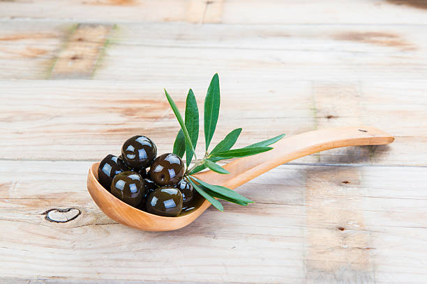 istock Wooden spoon with olives on the table 487160433