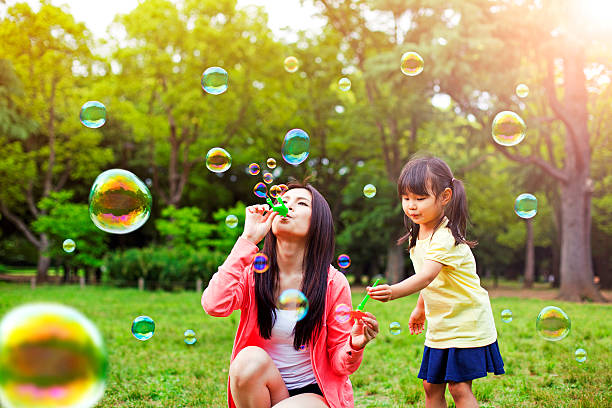 母と娘の楽しみ公園、石鹸の泡 - bubble wand child blowing asian ethnicity ストックフォトと画像