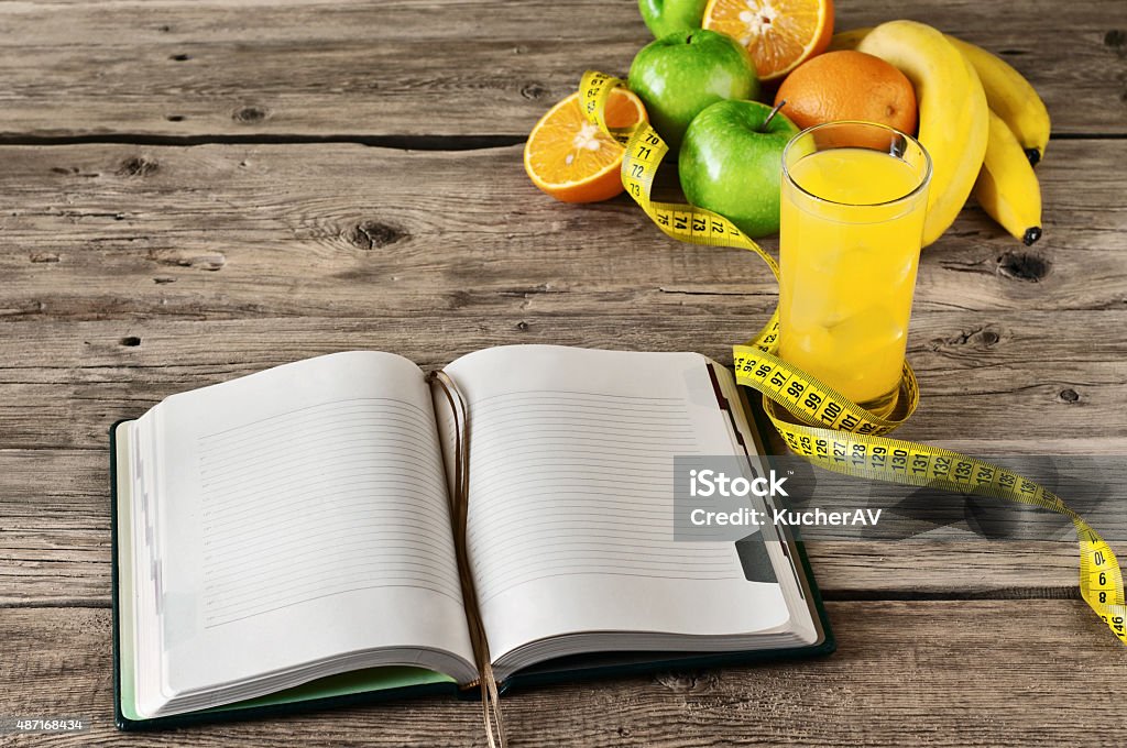 Open notebook for notes of fruit  and orange juice Open notebook for notes of fruit (apple, orange, banana) and orange juice on a wooden table. The concept of a healthy lifestyle and losing weight. Free space for text. Copy space. Top view 2015 Stock Photo