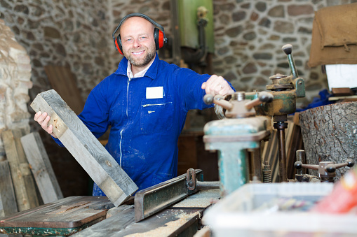 Happy professional woodworker on lathe at musical instrument workroom