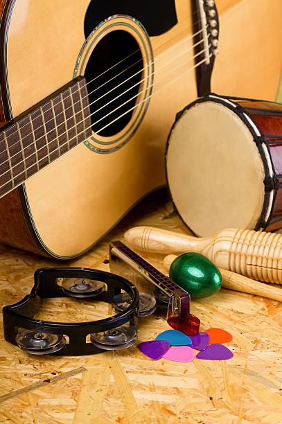 Set of musical instruments on OSB Vertical photo with several musical instruments on wooden OSB board as acoustic guitar with several colorful picks, guiro, harmonica, bongo and others. guiro stock pictures, royalty-free photos & images