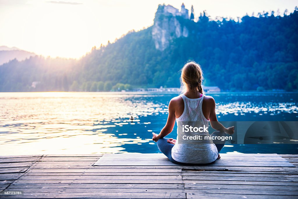 Meditation by the lake Young woman meditating by the lake Meditating Stock Photo