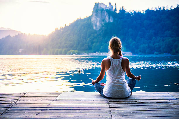 Meditation by the lake Young woman meditating by the lake good posture stock pictures, royalty-free photos & images