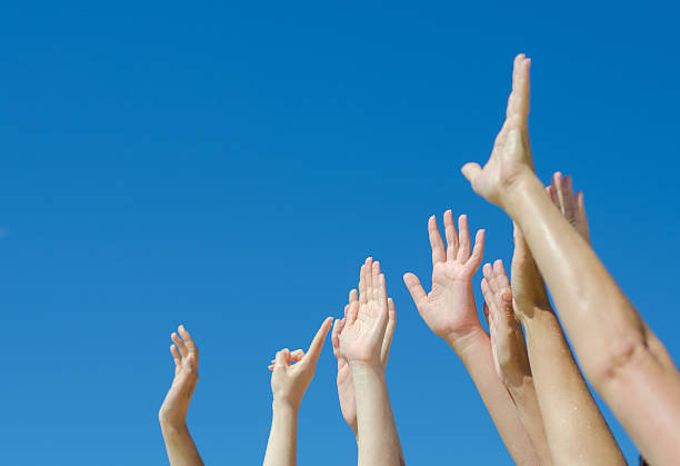 istock Many hands raised up against the blue sky. 487174131