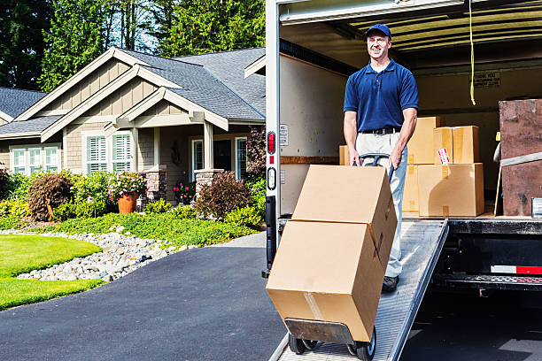 Delivery Man Unloading Truck Photo of a delivery man unloading (or loading) truck, walking cardboard boxes down ramp on a hand truck. moving van stock pictures, royalty-free photos & images