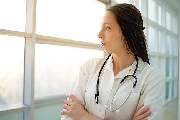 istock Pensive female doctor looking through the window. 487176236