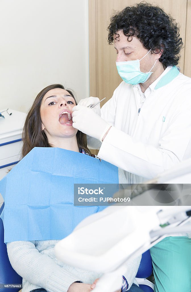 Dentist at work with dental tools Dentist using dental tools on young woman patient  - Tool for teeth cleaning  20-24 Years Stock Photo