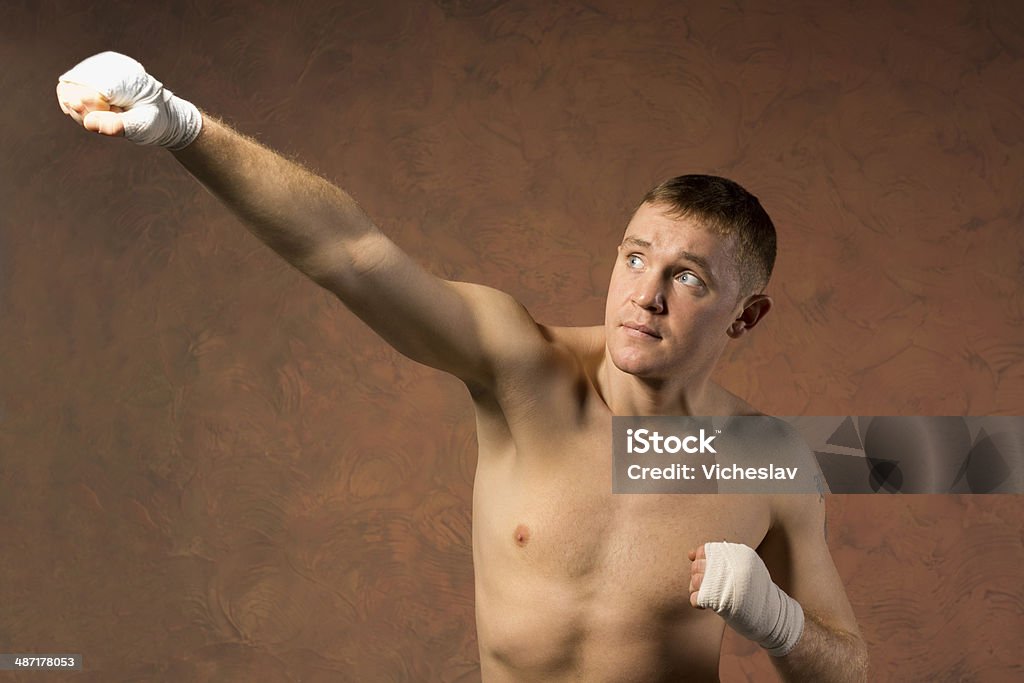 Young boxer throwing an upwards punch Young boxer throwing an upwards punch towards the top left corner of the frame with his bandaged fist and a look of determination Adolescence Stock Photo