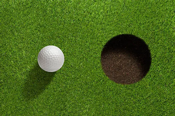 Golfball close to hole.
