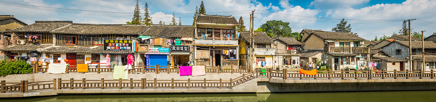 Shanghai, China - October 9, 2012: Colourful laundry drying in the warm sun in front of a row of homes beside the canal waterfront of Quibao, the traditional water village in the suburbs of Shanghai. Composite panoramic image created from twelve contemporaneous sequential photographs. 