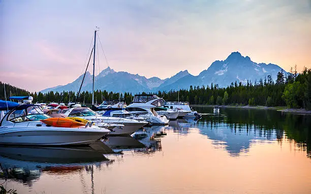 Boats on the lake at sunset in Colter bay with majestic Grand Teton Mountains in the Background