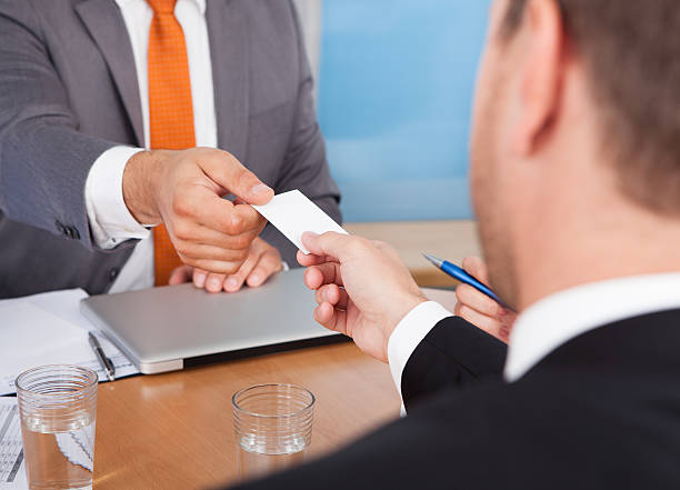 istock Two Businessmen Holding Card Over Desk 487203521