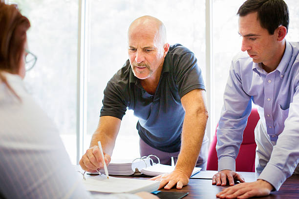 Troubled man pointing to small print on contract Troubled man pointing to small print on contract in front of unphased bureaucratic person. His friend is by his side. bureaucracy stock pictures, royalty-free photos & images