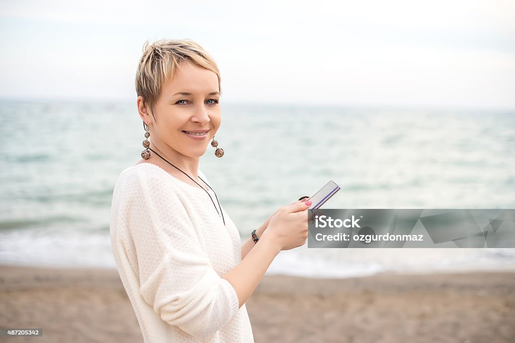 Woman using smart phone Woman using smart phone on the beach, Blurred background. There is copy space in right side of image for your text. Horizontal composition. Image taken with Nikon D800 and developed from Raw. Beach Stock Photo